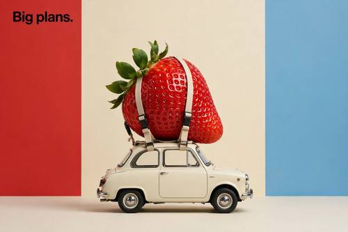 A giant strawberry strapped to the roof of a tiny vintage car, the line 'Big plans.' in the top left. Side view, the car centered. Red, cream and sky blue backdrop. Deadpan and funny. Silly surreal photo: an absurd mix of scale or objects shown completely deadpan, crisp clean studio light, smooth real materials, a bright flat seamless color backdrop, soft simple shadows, a minimal composition with one short line in a bold sans-serif. Witty, clean and photorealistic.