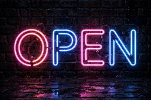 Glowing pink and blue neon sign spelling OPEN on a dark brick wall, realistic neon tubes, soft glow reflections, night mood